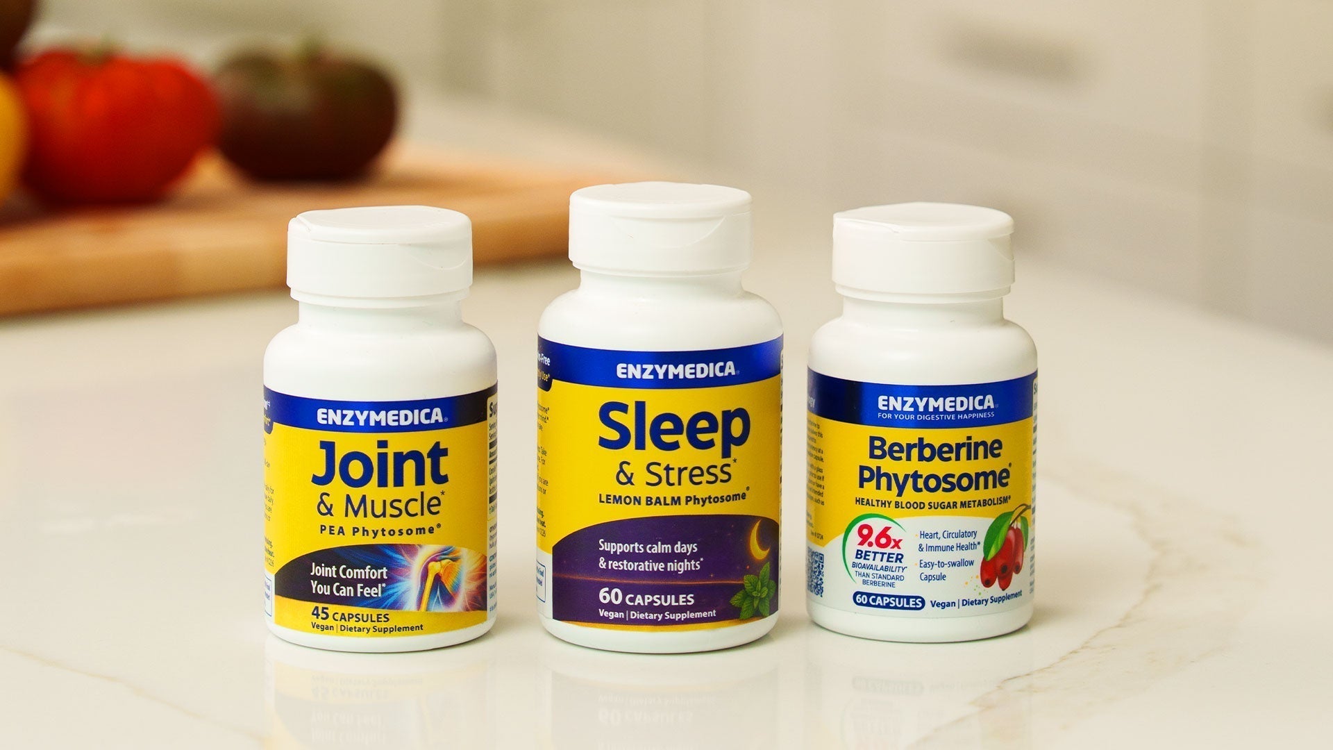 Three Enzymedica supplement bottles on a kitchen counter: Joint & Muscle PEA Phytosome, Sleep & Stress Lemon Balm Phytosome, and Berberine Phytosome.