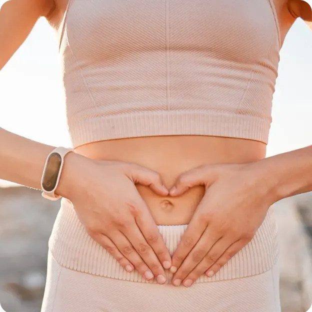 Woman holding her stomach making a heart shape with her hands.