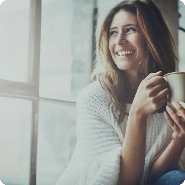Woman drinking coffee looking out of the window.