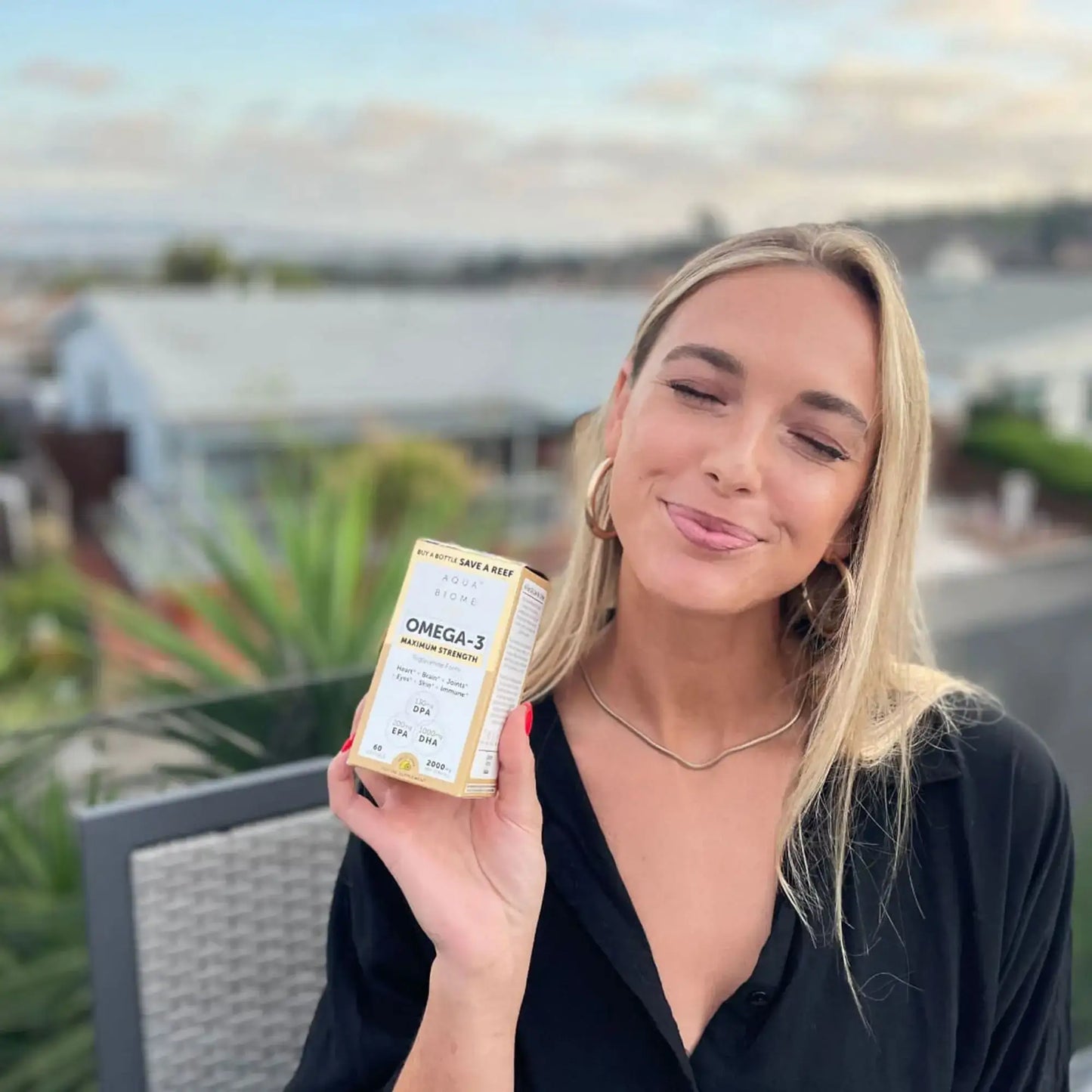 This image shows a woman holding a carton of aqua biome fish oil max strength