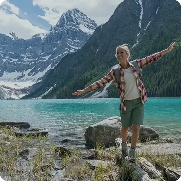A woman balancing on rocks overlooking mountains and a lake