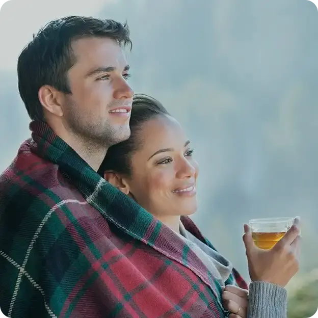 Man and woman cuddling drinking a beverage outside.