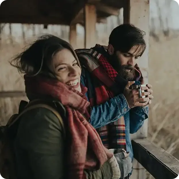 A man and woman enjoying a hot drink in a porch during the fall.